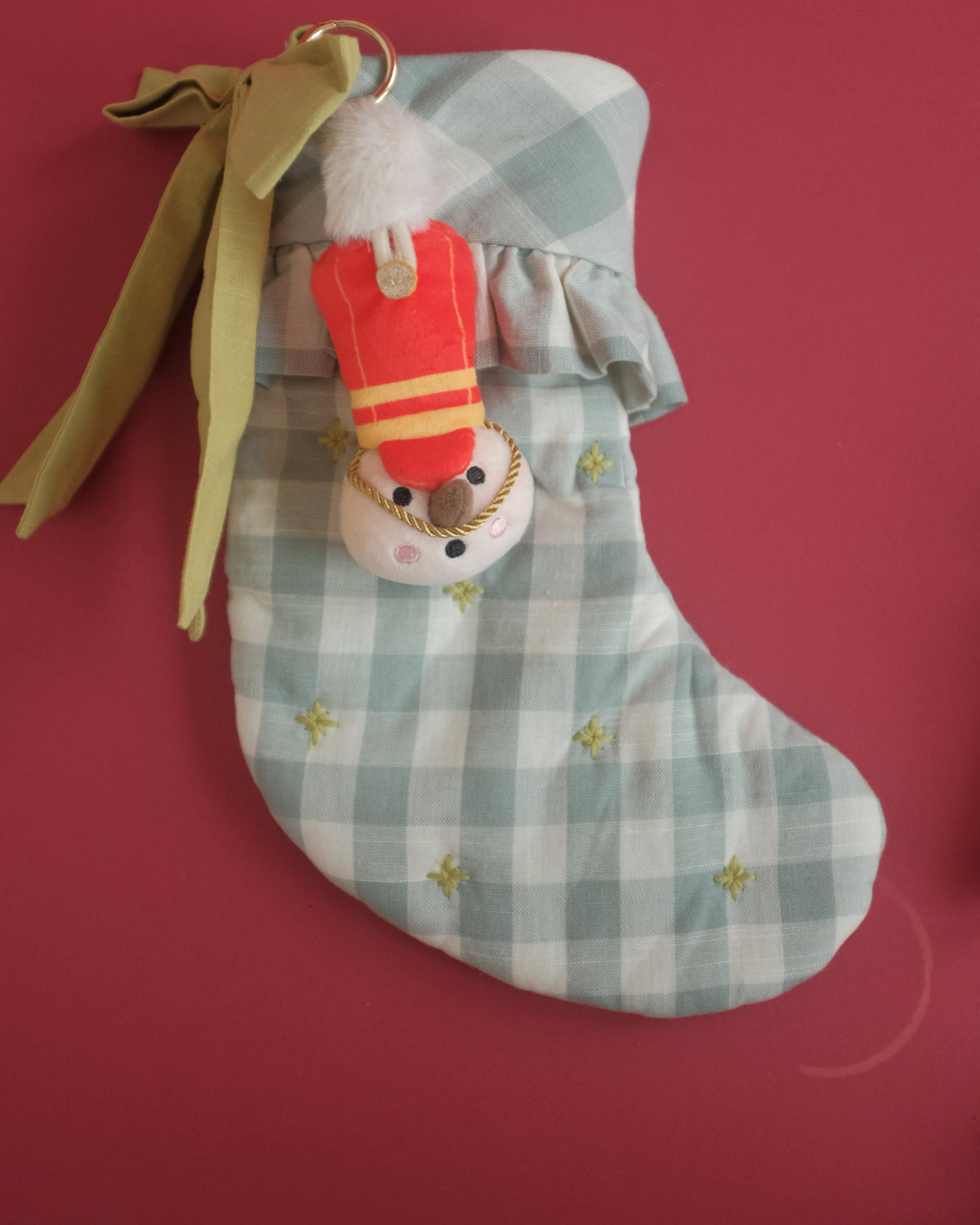 The Merry Marcher bag charm tucked into a gingham Christmas stocking