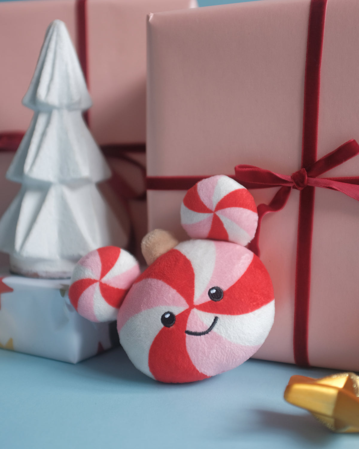 Peppermint Pal bag charm beside pink wrapped gifts, a silver tree and a gold star