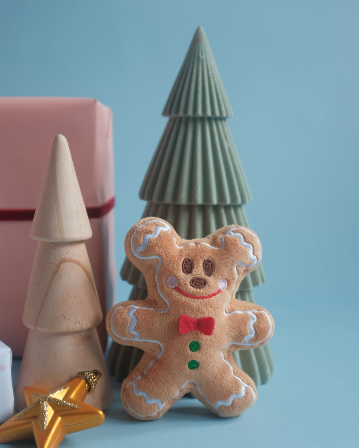 Gingerbread Gent bag charm beside a green tree and a gold star on a blue backdrop
