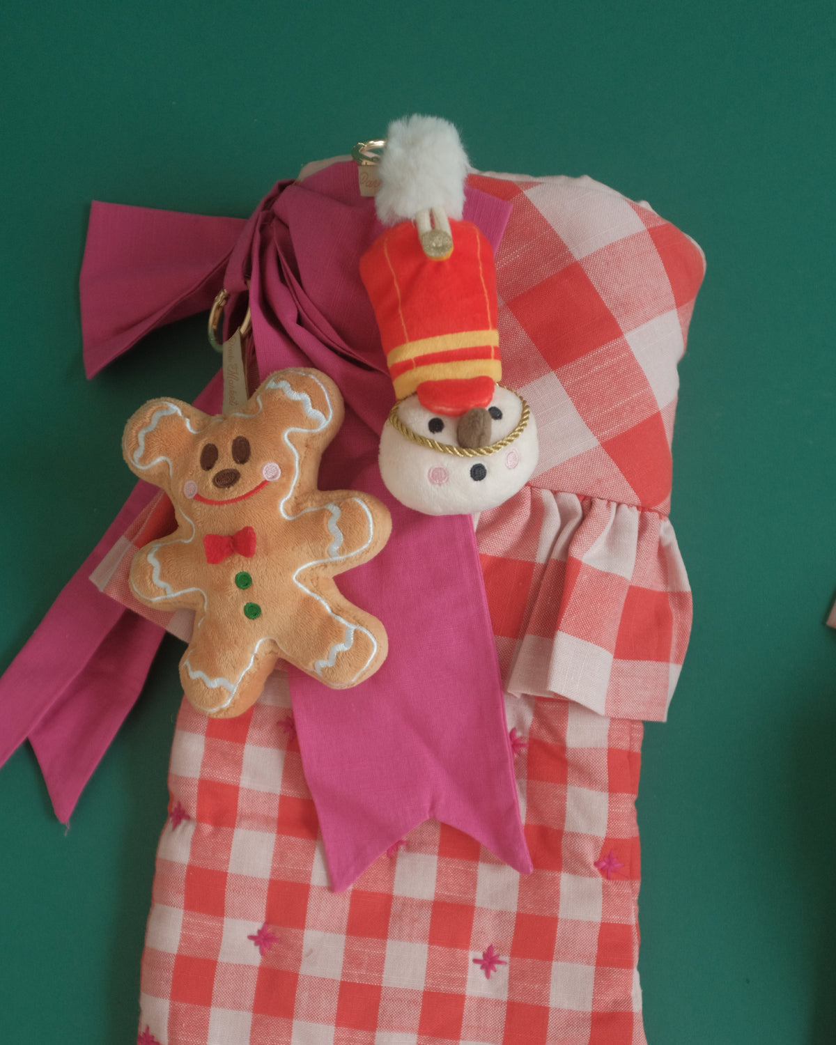 Gingerbread Gent and The Merry Marcher bag charms on a red gingham stocking with a pink bow