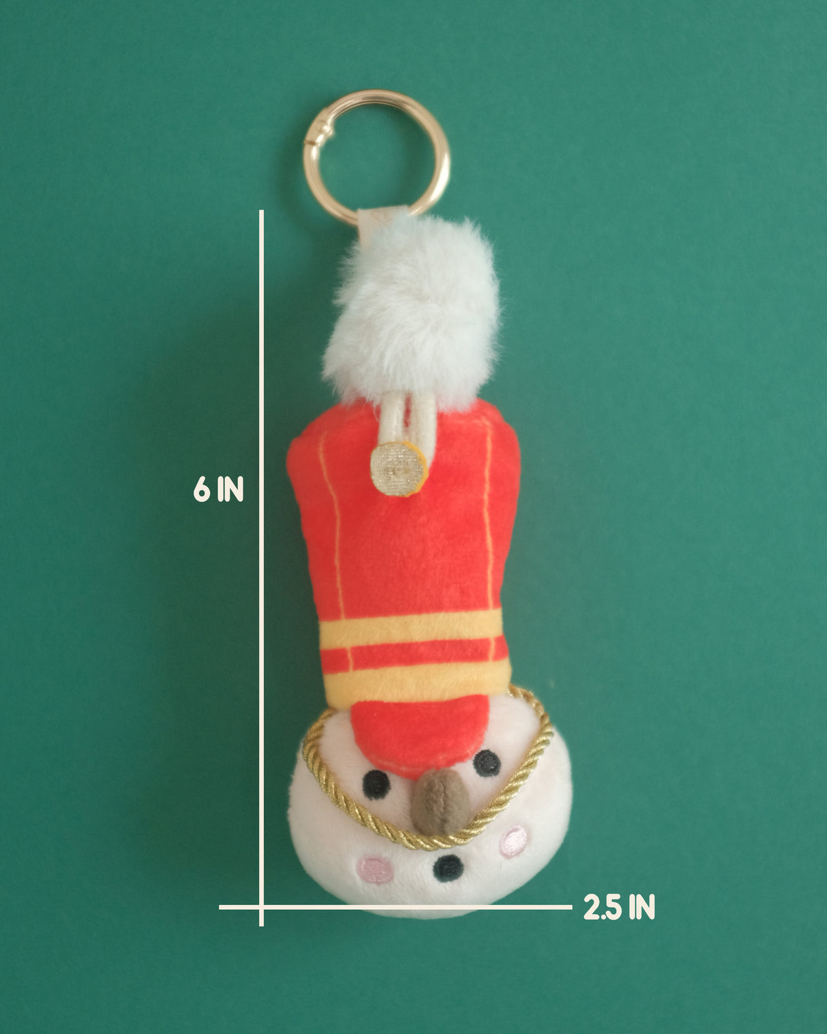 Toy soldier plush bag charm with a red hat and white plume; measurement lines show 6 inches tall by 2.5 inches wide