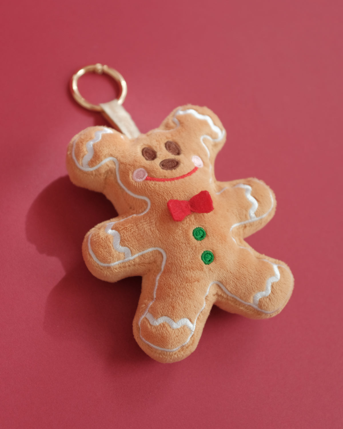 Gingerbread Gent bag charm at an angle, showing the embroidered frosting and green buttons
