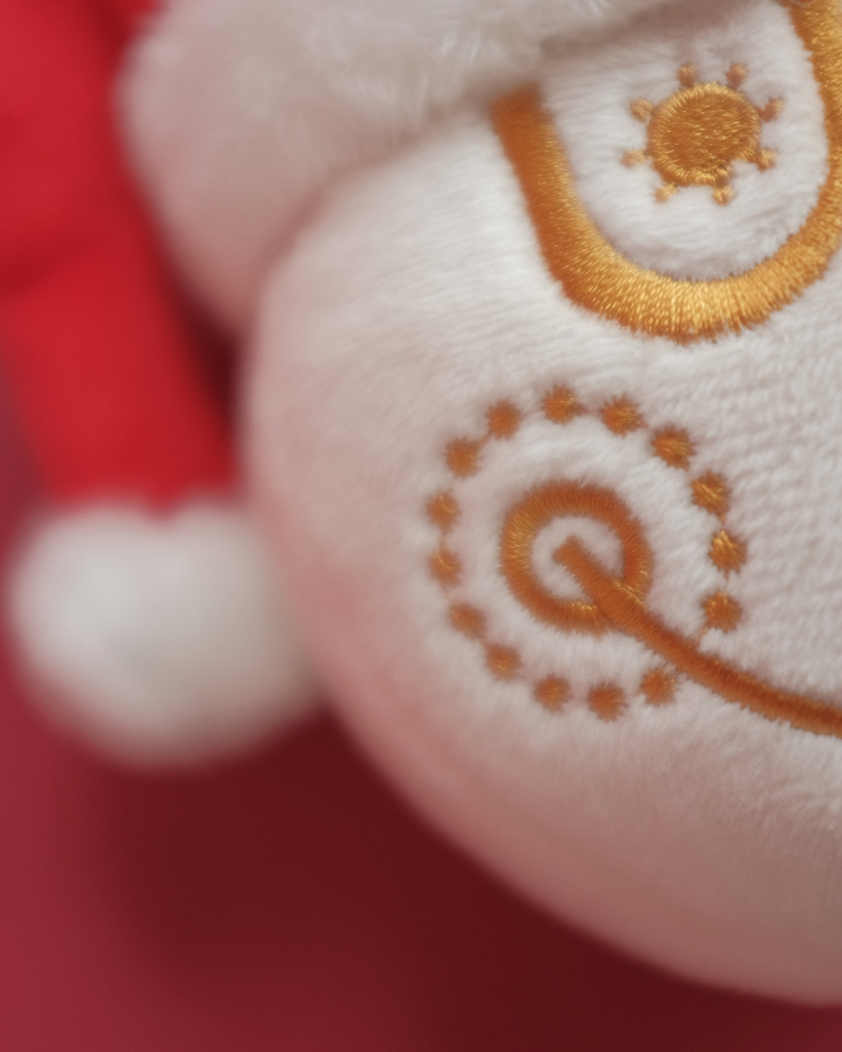 Macro close-up of Tinsel Time's gold-thread embroidery and plush white Santa hat trim