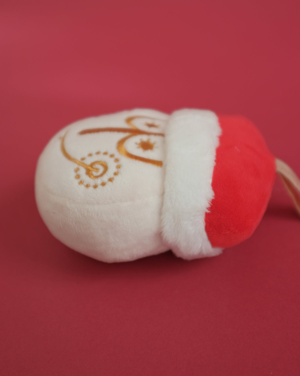 Tinsel Time bag charm lying on its side, showing the gold embroidery and Santa hat