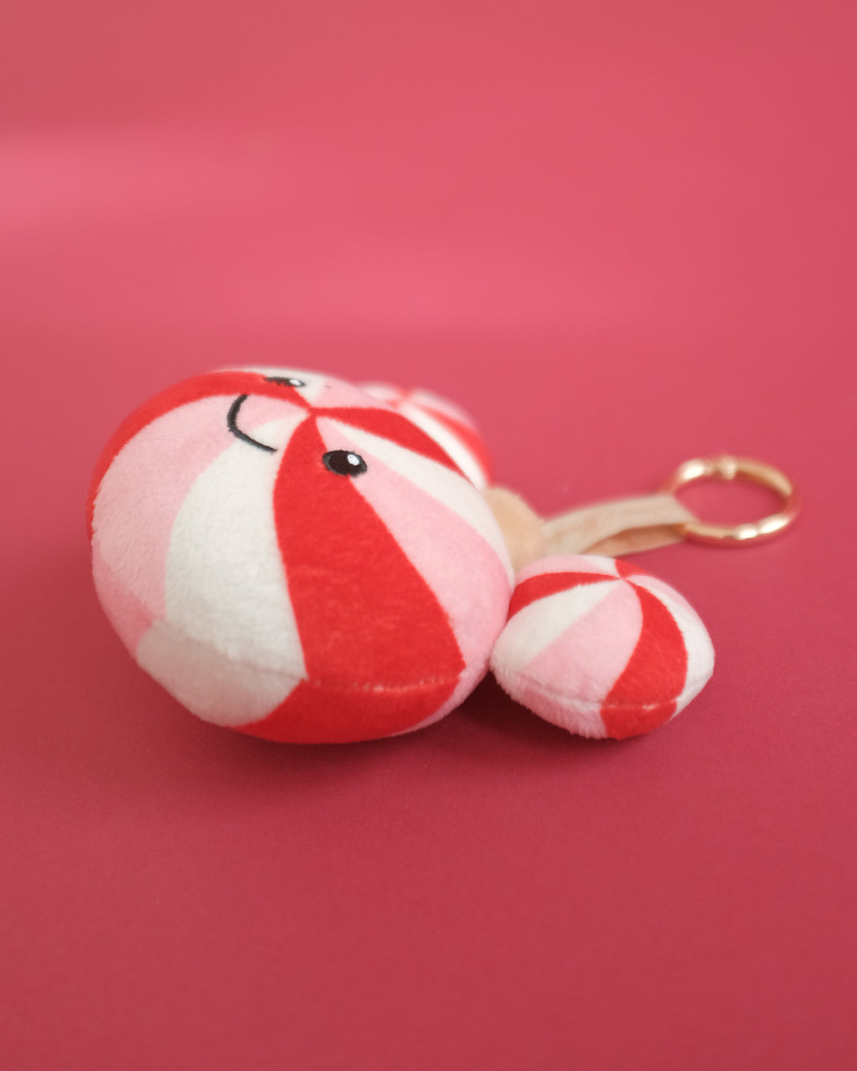 Side view of the Peppermint Pal bag charm showing its round plush shape and gold clip