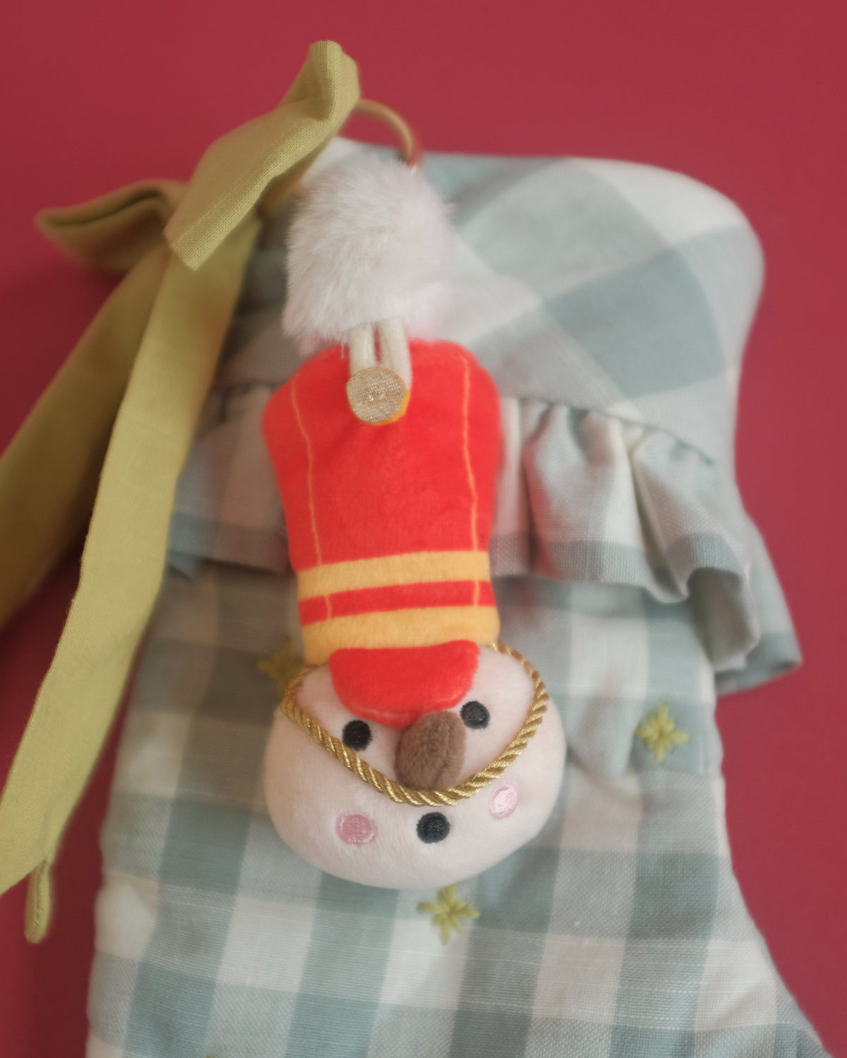 The Merry Marcher bag charm on a gingham Christmas stocking with a green ribbon