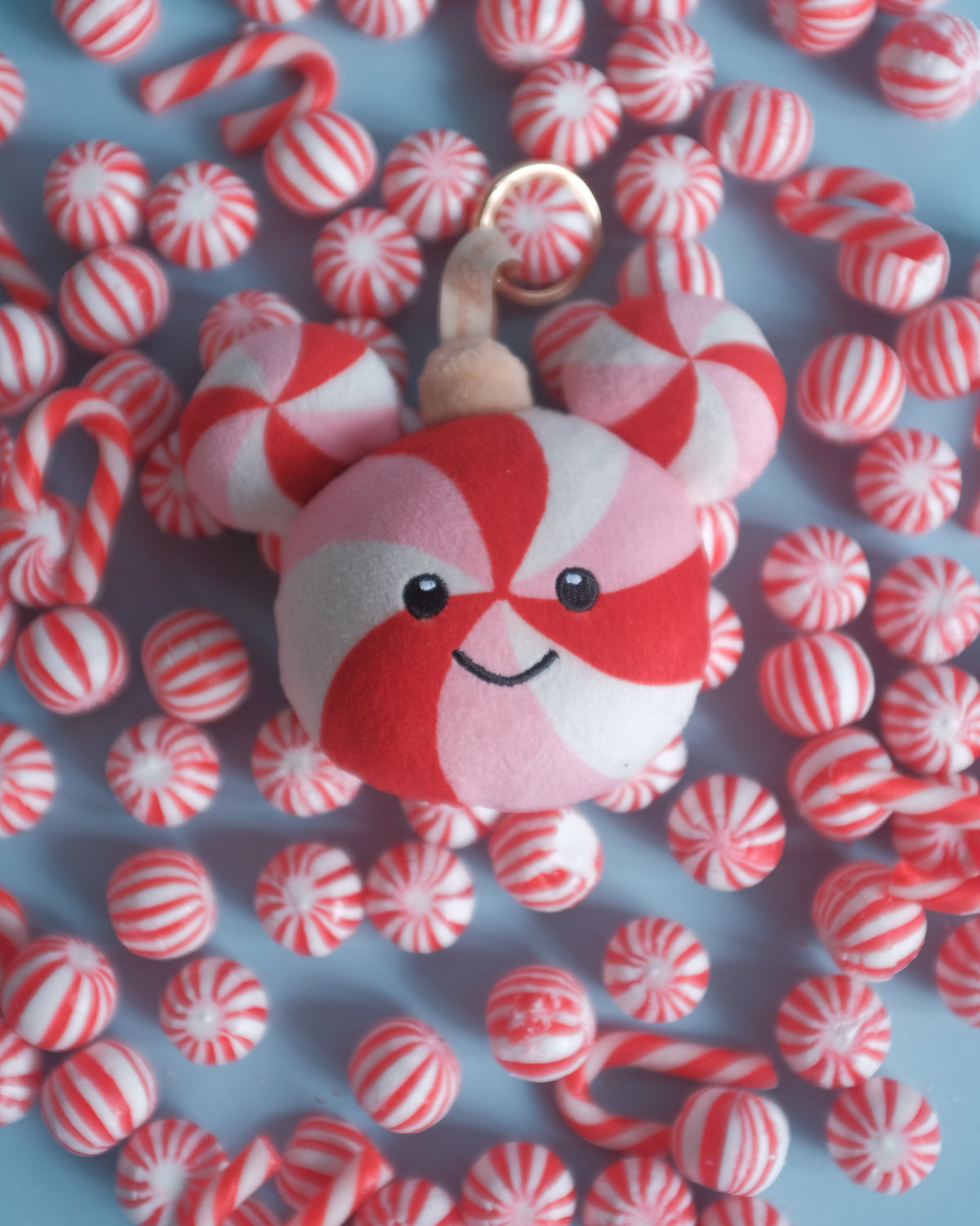 Peppermint Pal bag charm on a pile of red and white peppermint candies